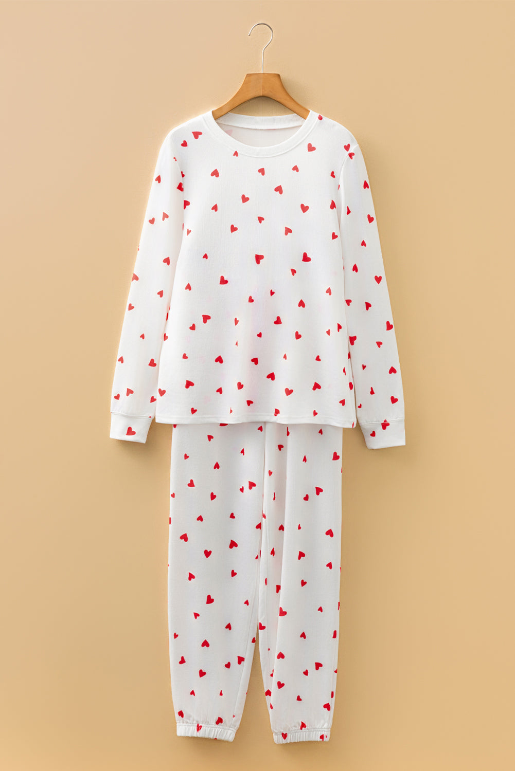 White pajama set with red heart patterns on a beige background
