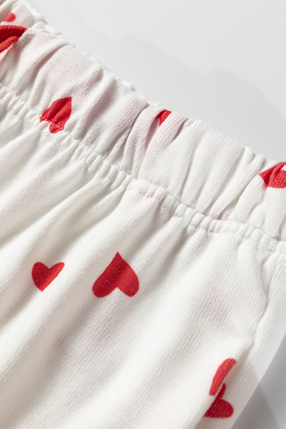 White fabric with red heart patterns on a light gray background