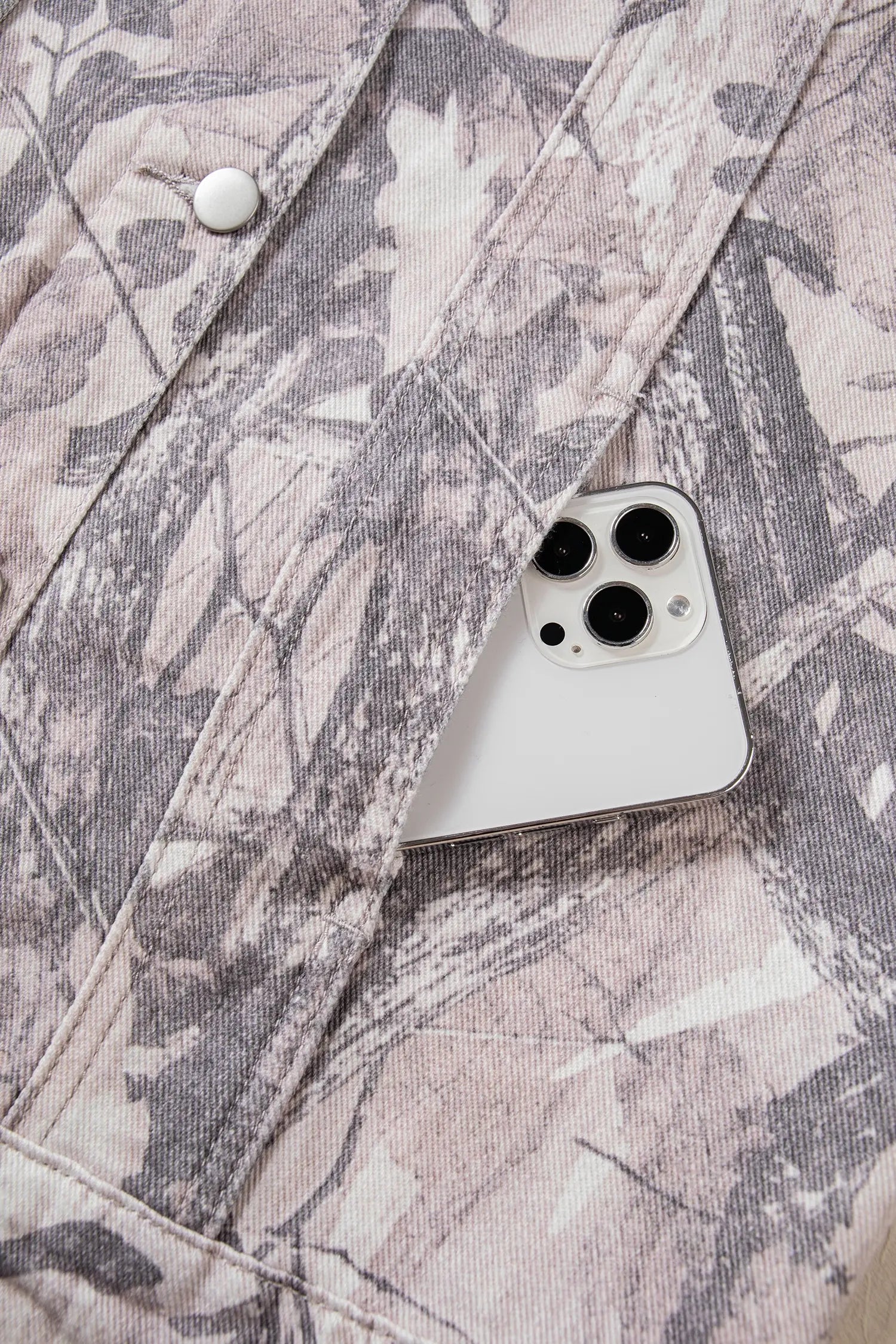 Close-up of camouflage button-up shirt with a white smartphone tucked into the front pocket.
