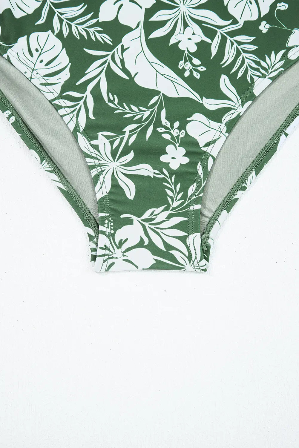 Green bikini bottom with white floral pattern on a white background