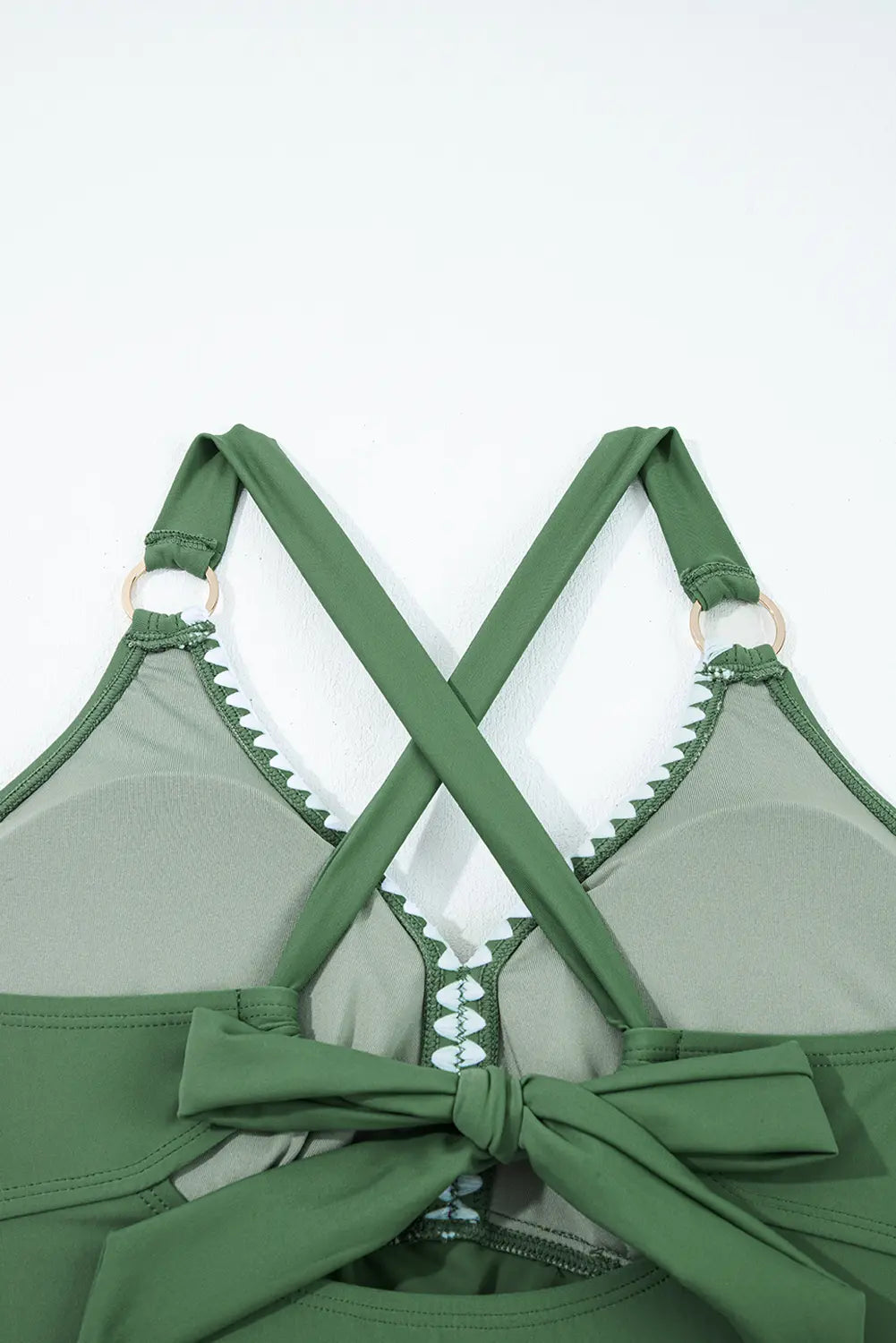 Green bikini top with criss-cross straps and bow details on a white background