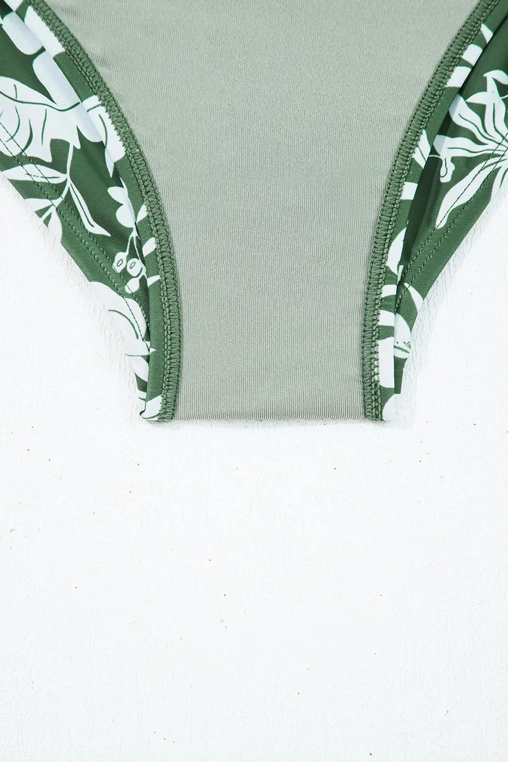 Green and white floral patterned garment on a light gray background
