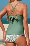 Green tankini top with floral bottom worn by a person on a beach.