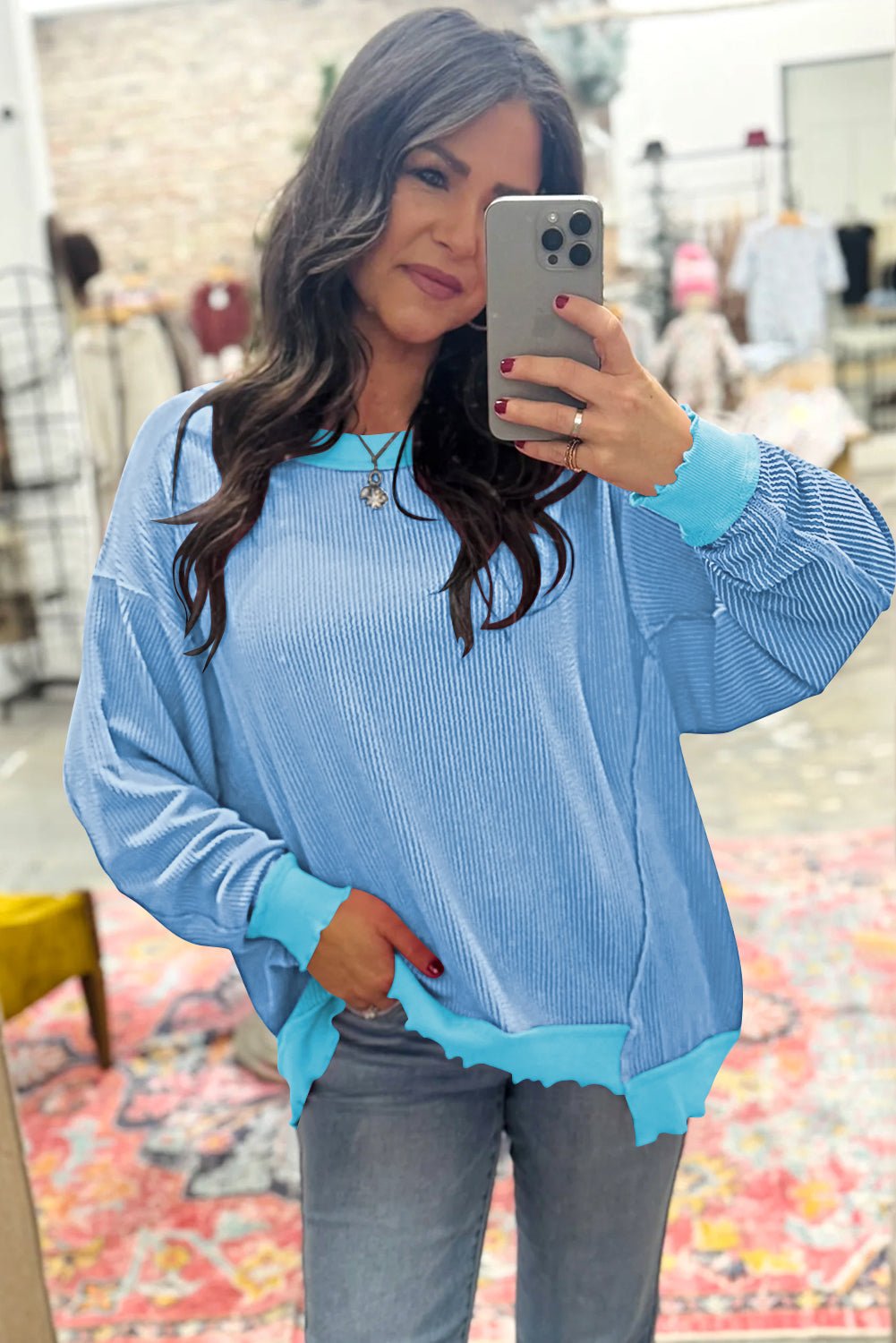 Woman taking a selfie wearing a blue sweater in a store setting