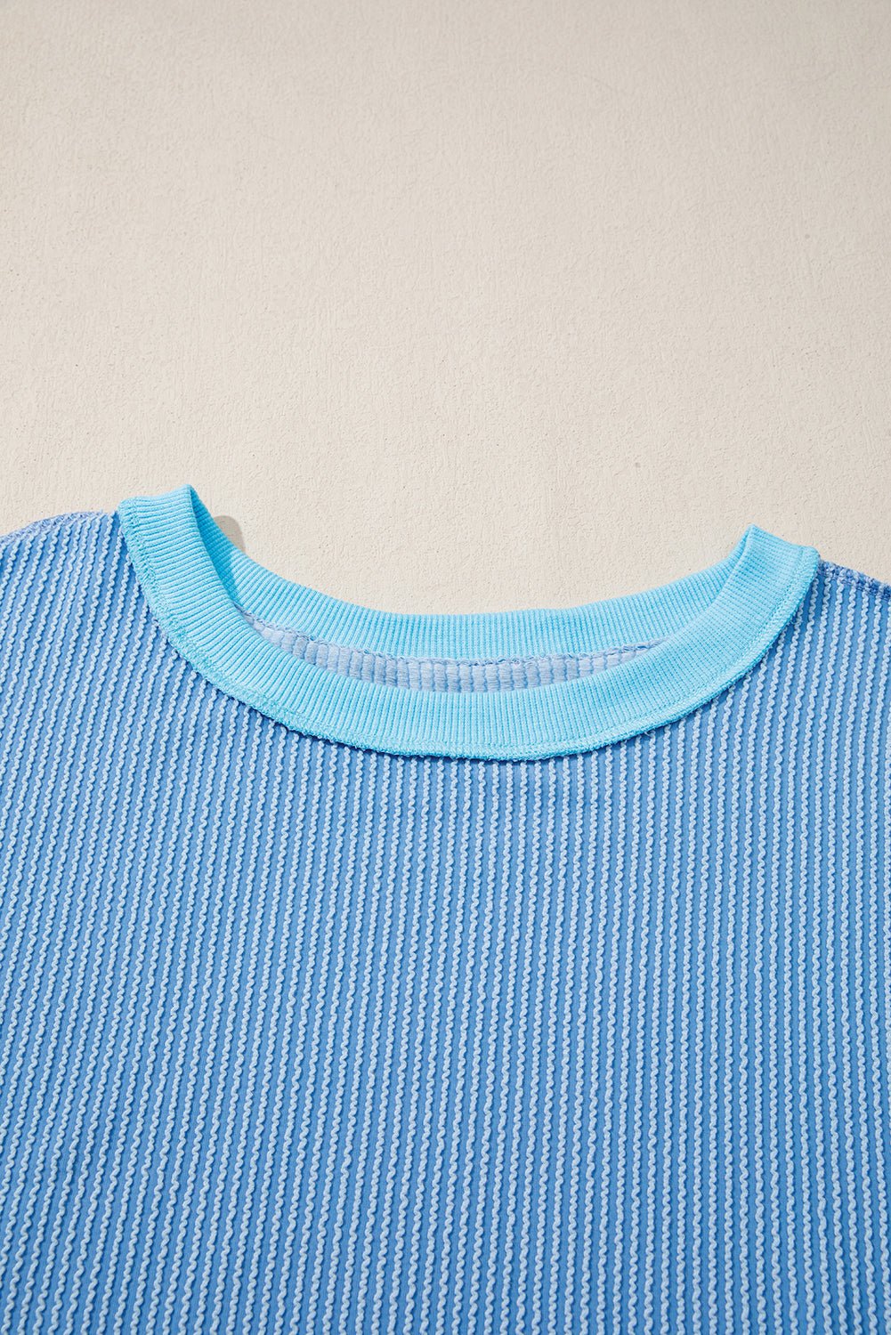 Close-up of a blue textured sweater with a beige background
