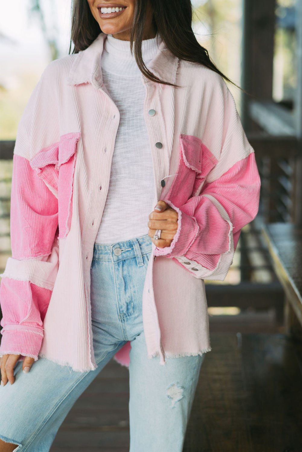Person wearing a pink and white jacket with light blue jeans outdoors.
