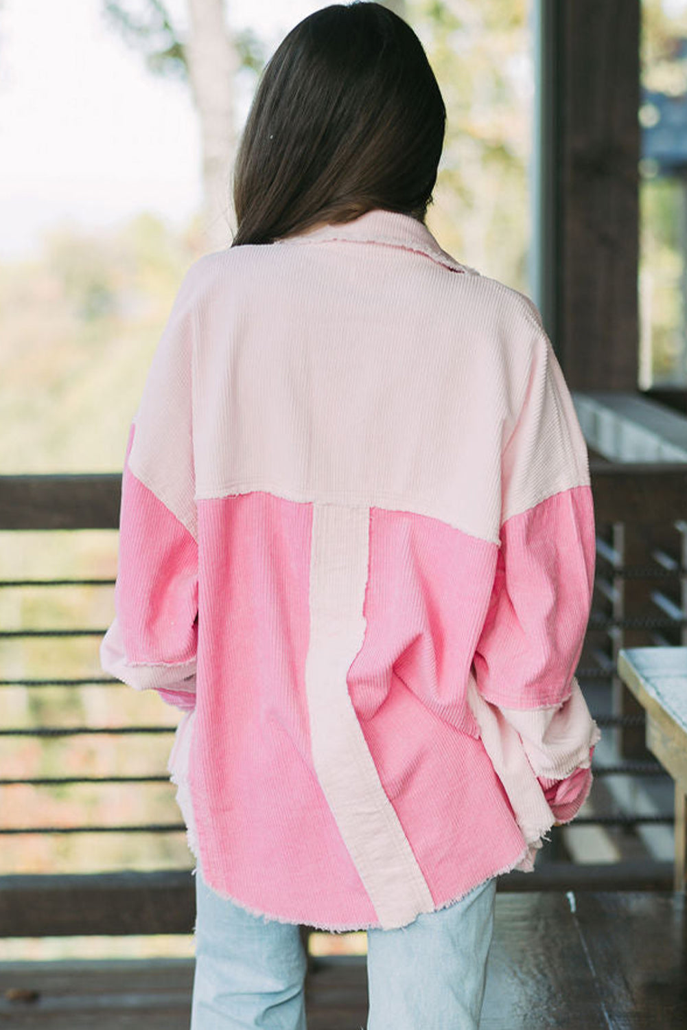 Person wearing a pink and beige jacket sitting outdoors.