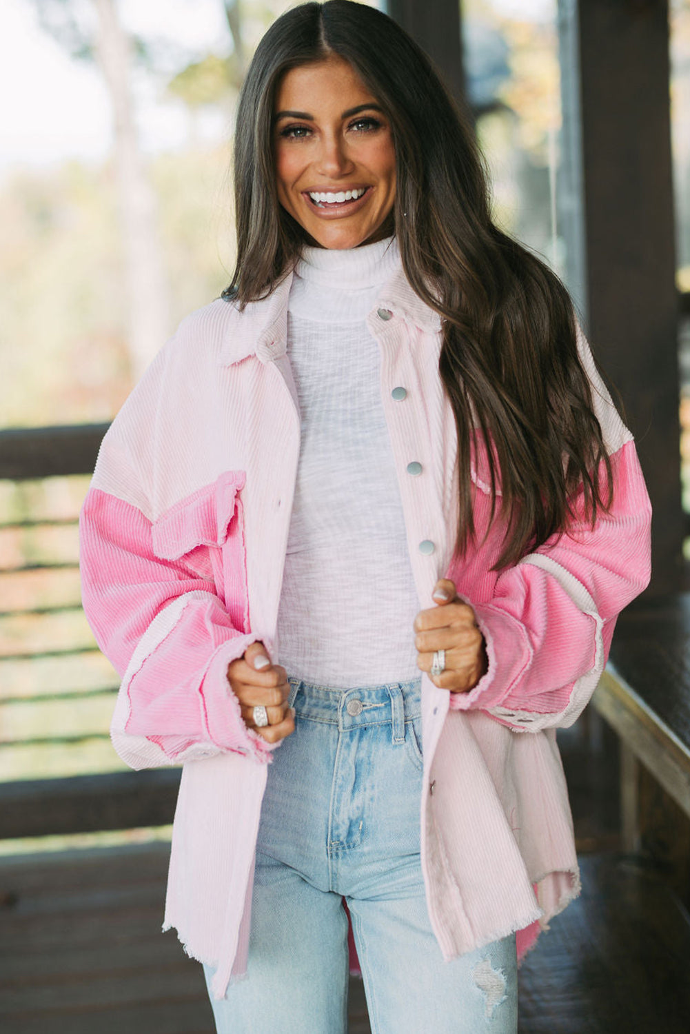 Woman wearing a pink and white jacket with a blurred outdoor background