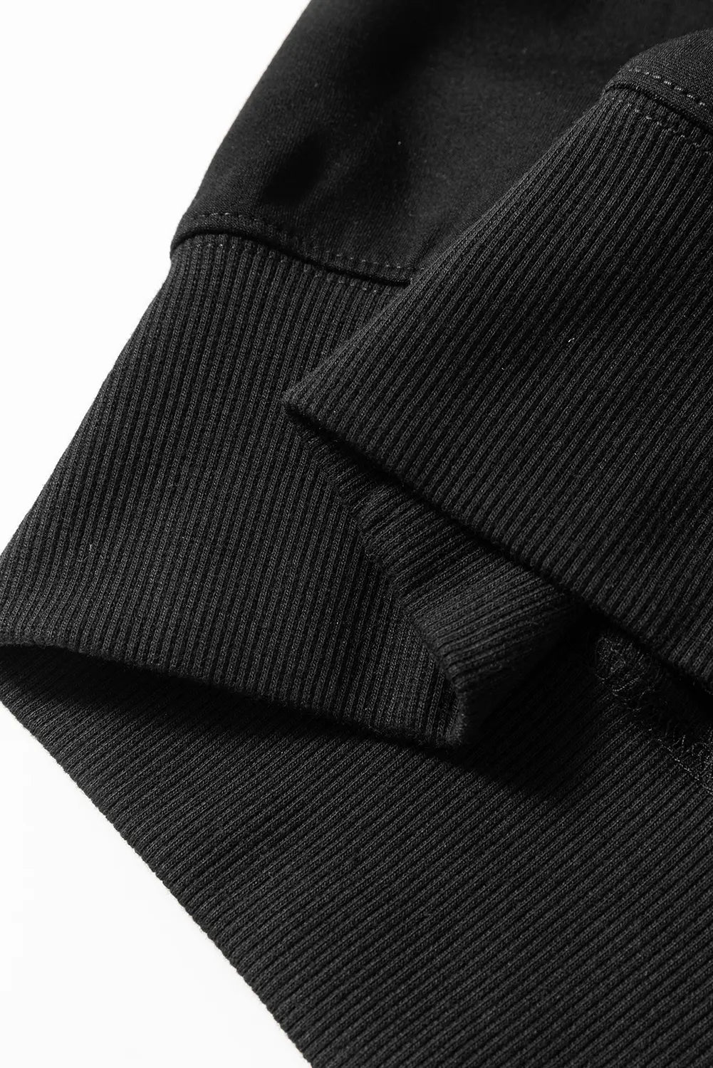 Close-up of black ribbed knit fabric with textured cuff detail.