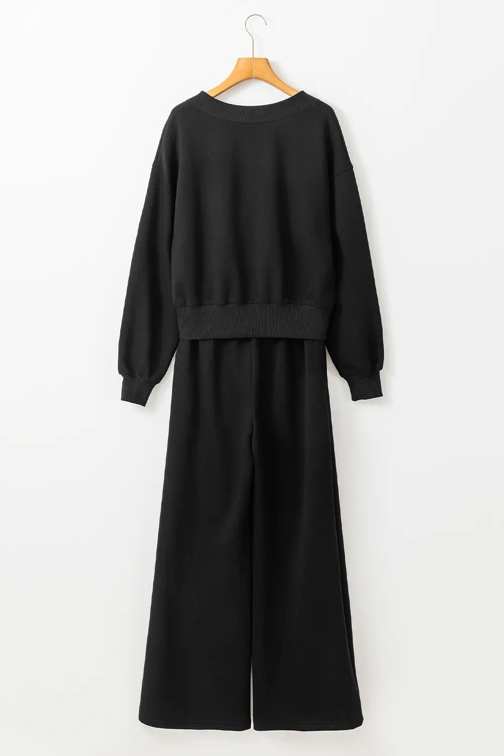 Black outfit with wide-leg pants on a hanger against a white background