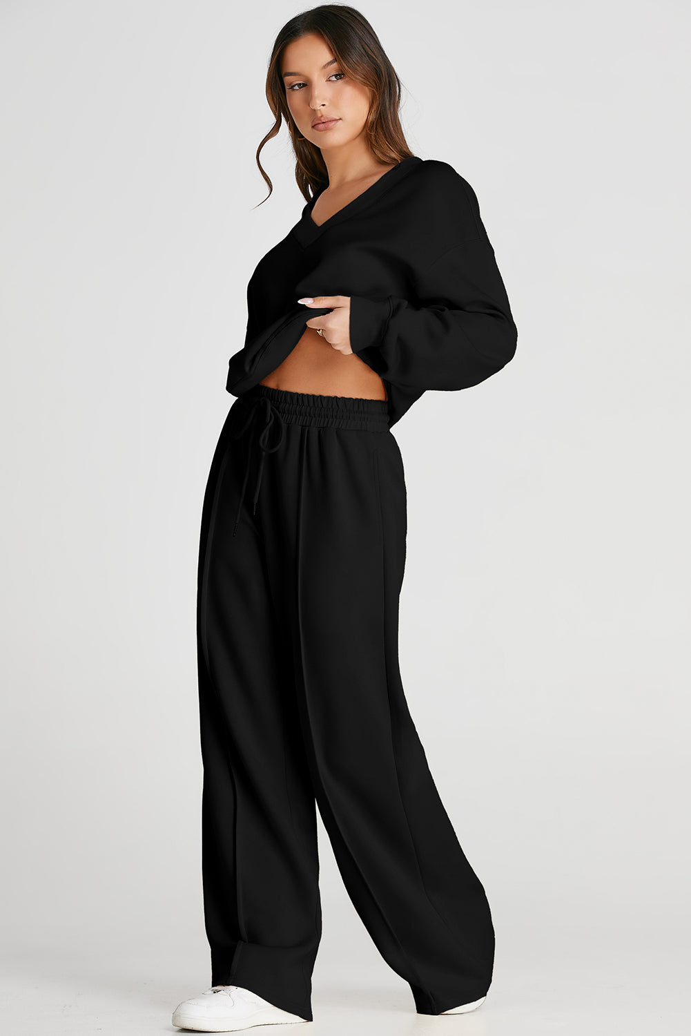 Woman wearing a black outfit with wide-leg pants on a white background