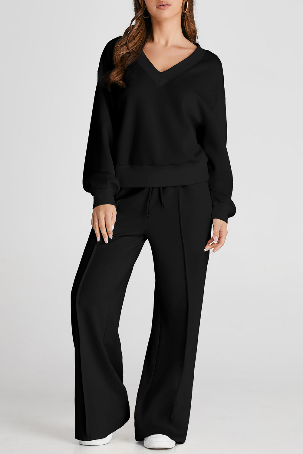 Woman in black V-neck loungewear set with wide-leg drawstring pants.
