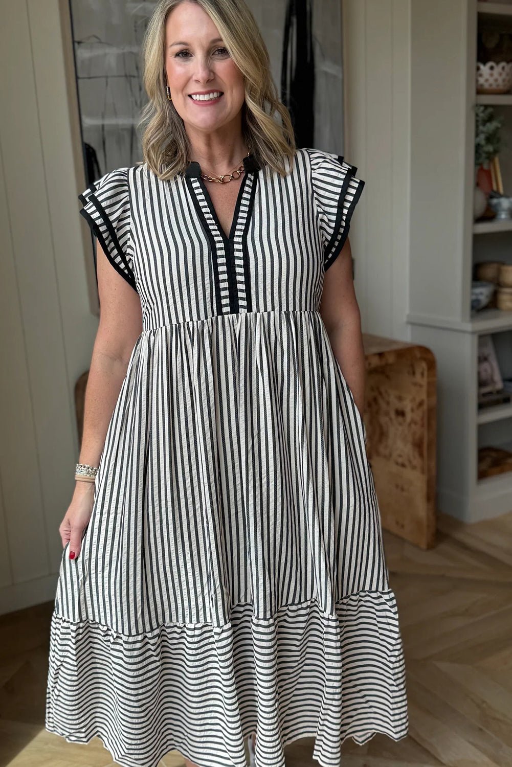 Woman wearing a black and white striped dress indoors.