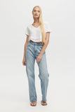 Woman wearing light blue jeans and a white top on a white background