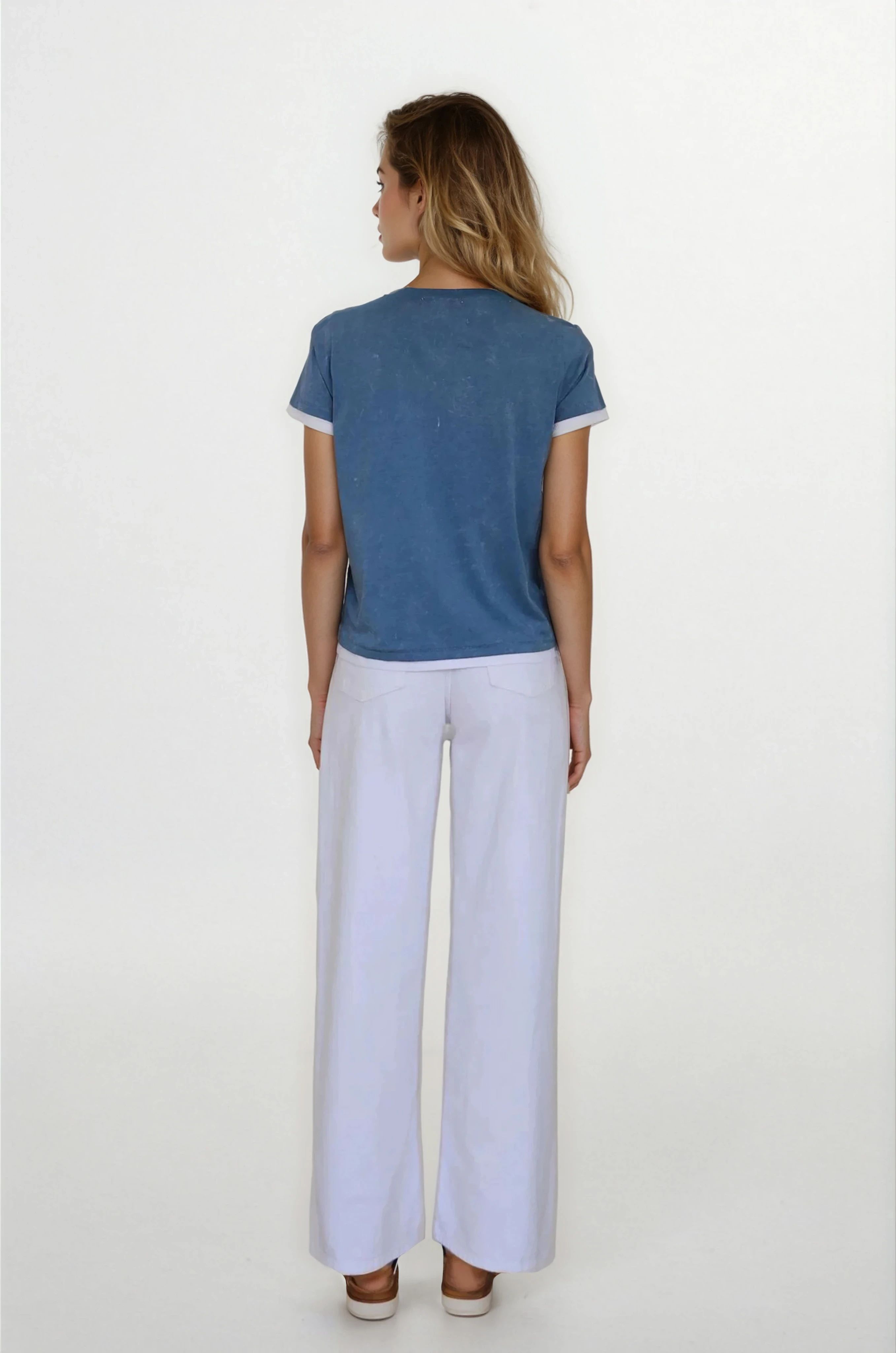 Woman wearing a blue top and white pants on a white background