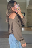 Woman taking a mirror selfie wearing a brown off-shoulder top and blue jeans.