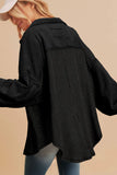 Person wearing a black jacket with a brand logo on a beige background