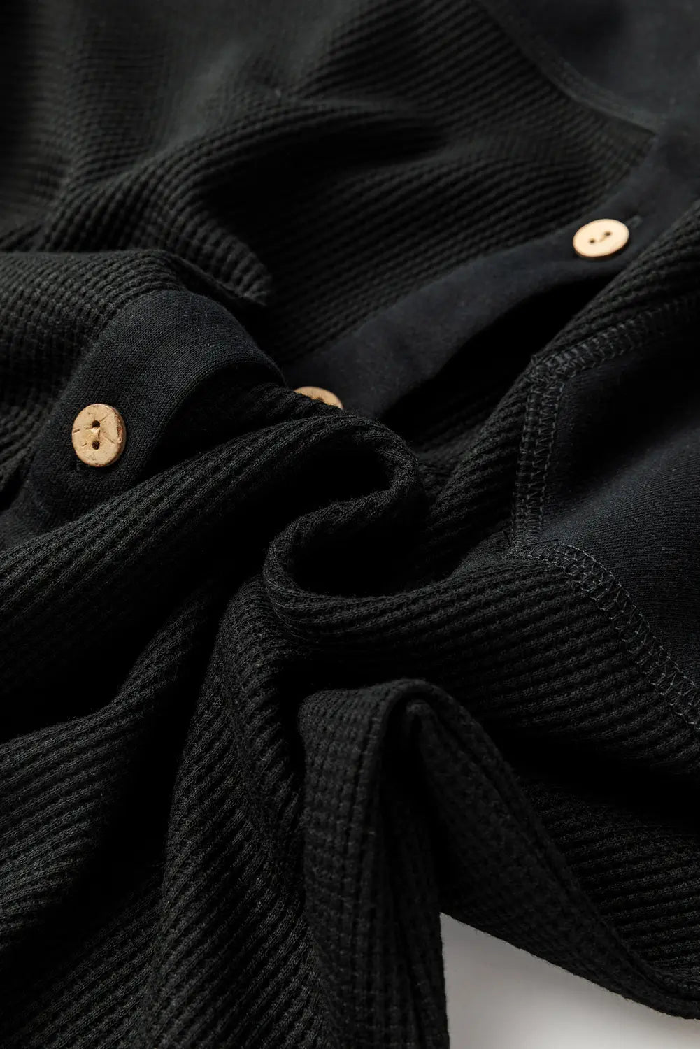 Close-up of a black textured fabric with gold buttons