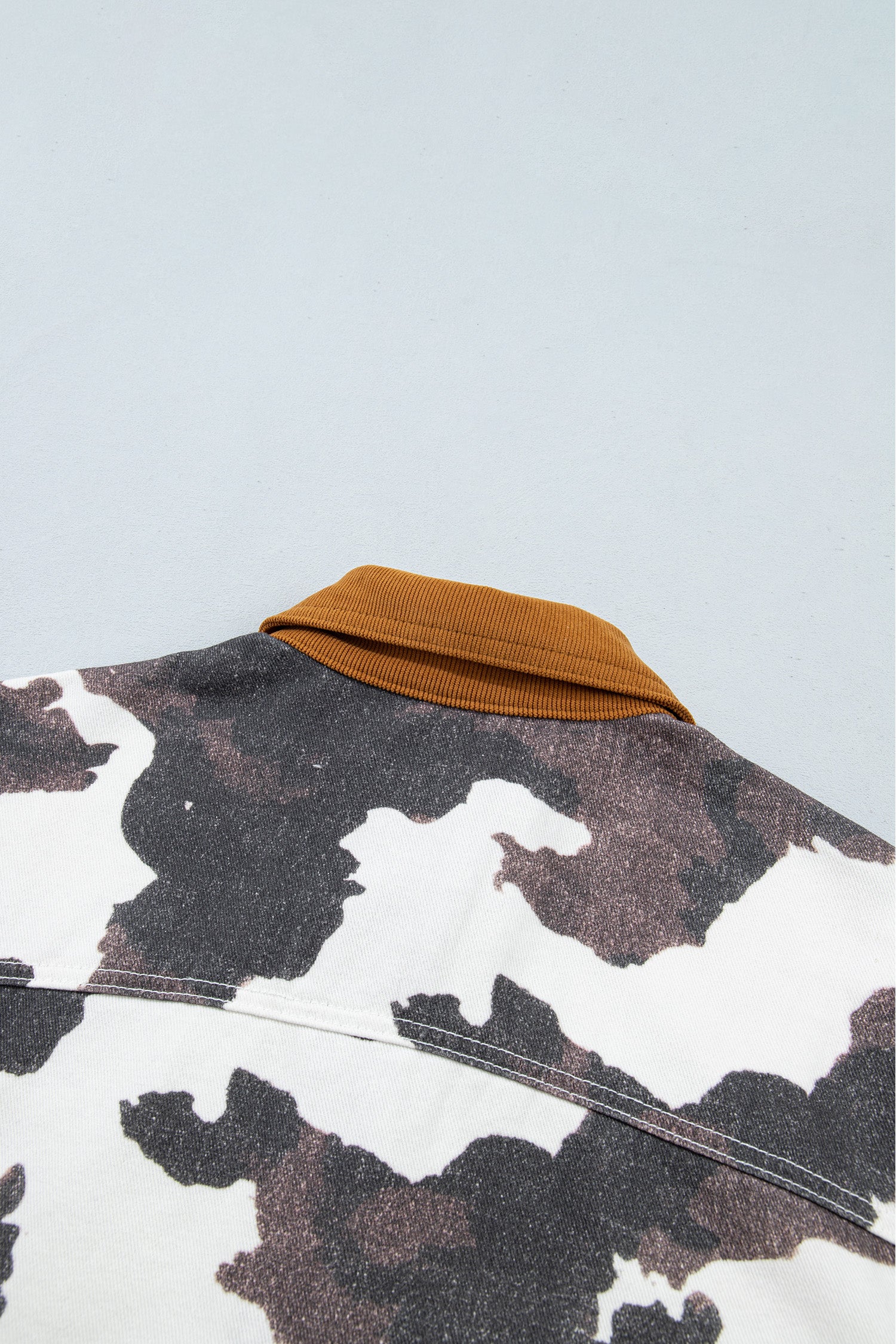 Close-up of camouflage jacket back with solid mustard yellow ribbed collar 