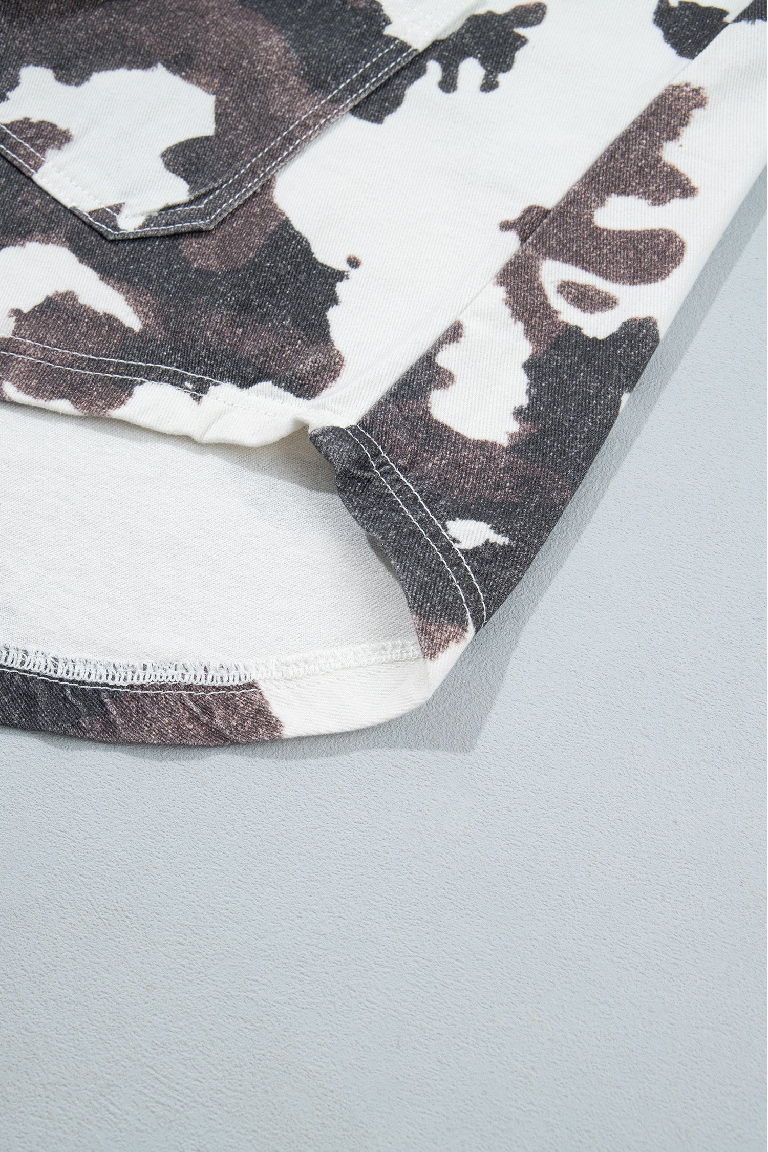 Close-up of white cotton garment with brown and black cow-print pattern