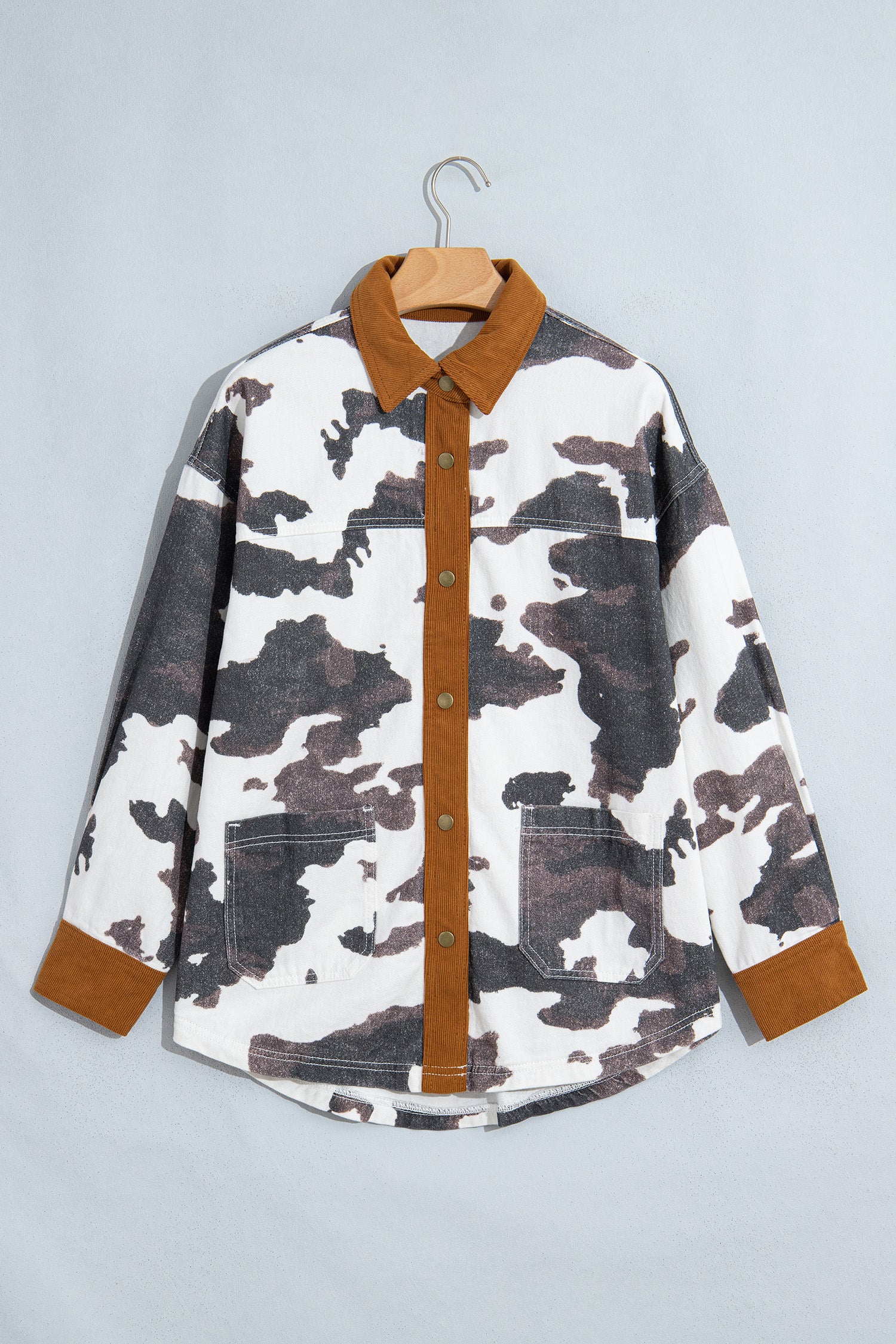 Long-sleeve camouflage shirt with brown, gray, and white pattern and brown contrast trim on hanger.