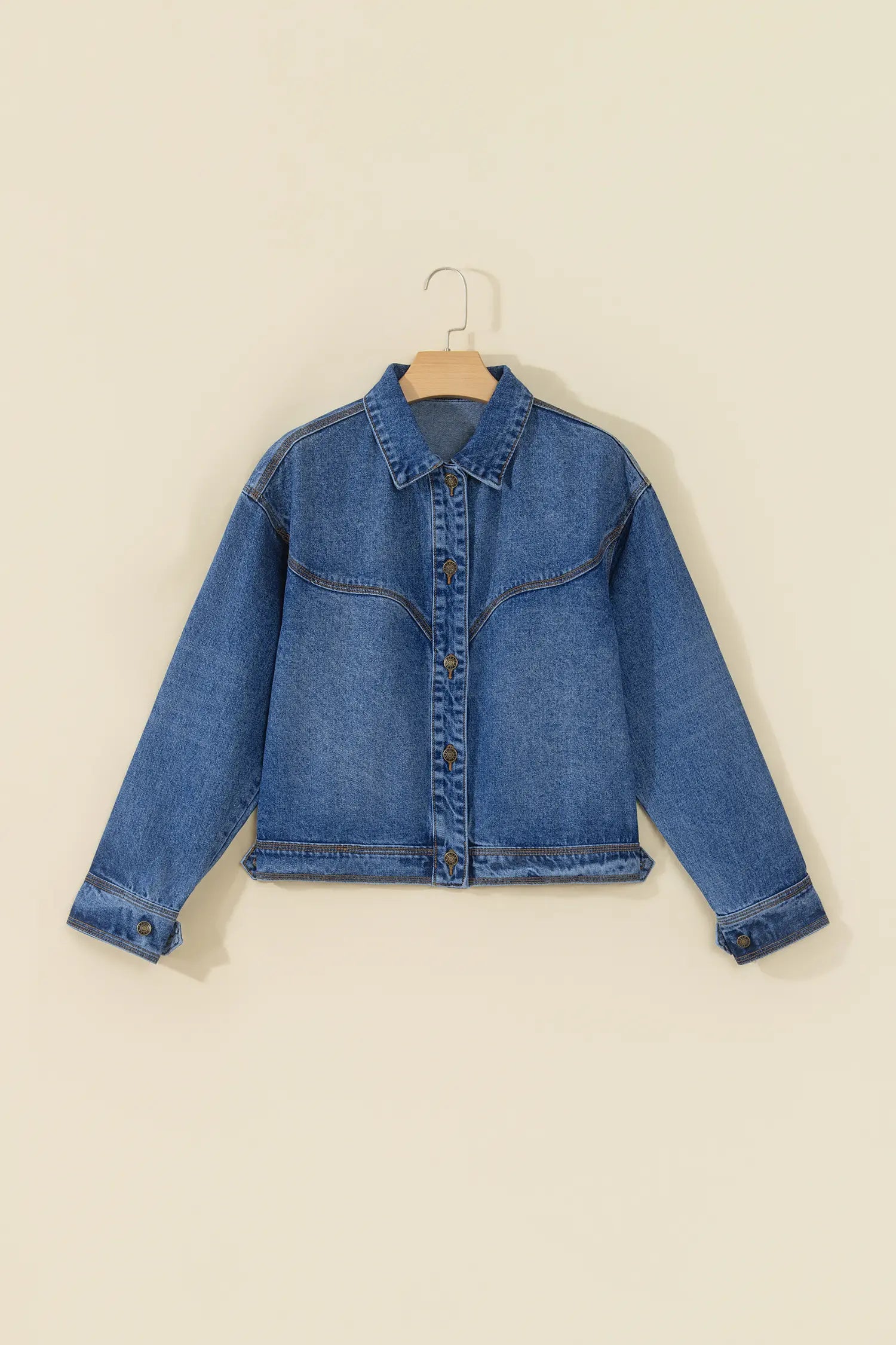 A cropped blue denim jacket with long sleeves, displayed