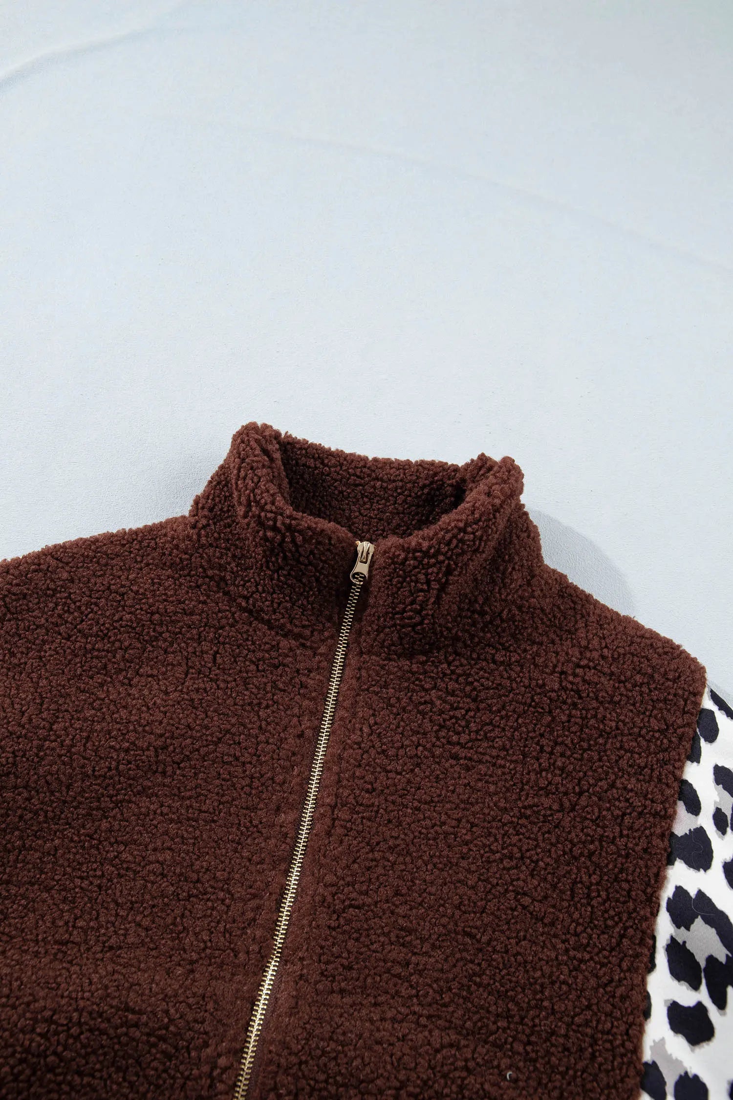 Close-up of brown sherpa vest with high collar and gold zipper.