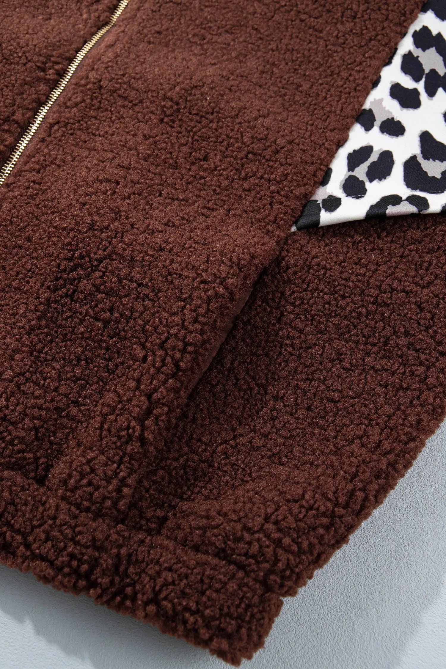Close-up of brown sherpa jacket with gold zipper and leopard-print lining.
