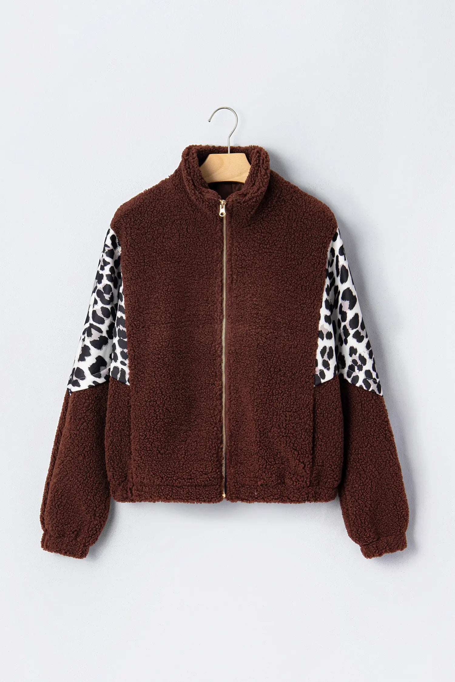 Brown sherpa fleece zip-up jacket with leopard-print sleeves on hanger.