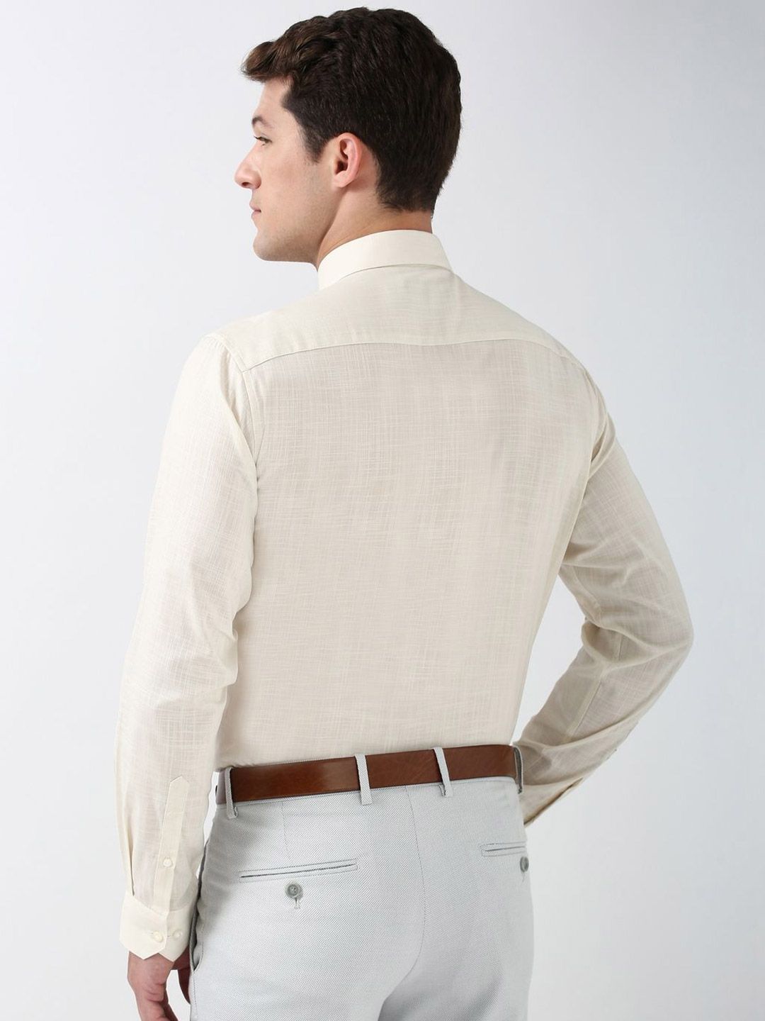 Man wearing a beige shirt and light gray pants on a white background