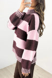 A woman wearing a fuzzy knit mock-neck sweater with large horizontal stripes in dark plum and light pink, paired with brown pants.