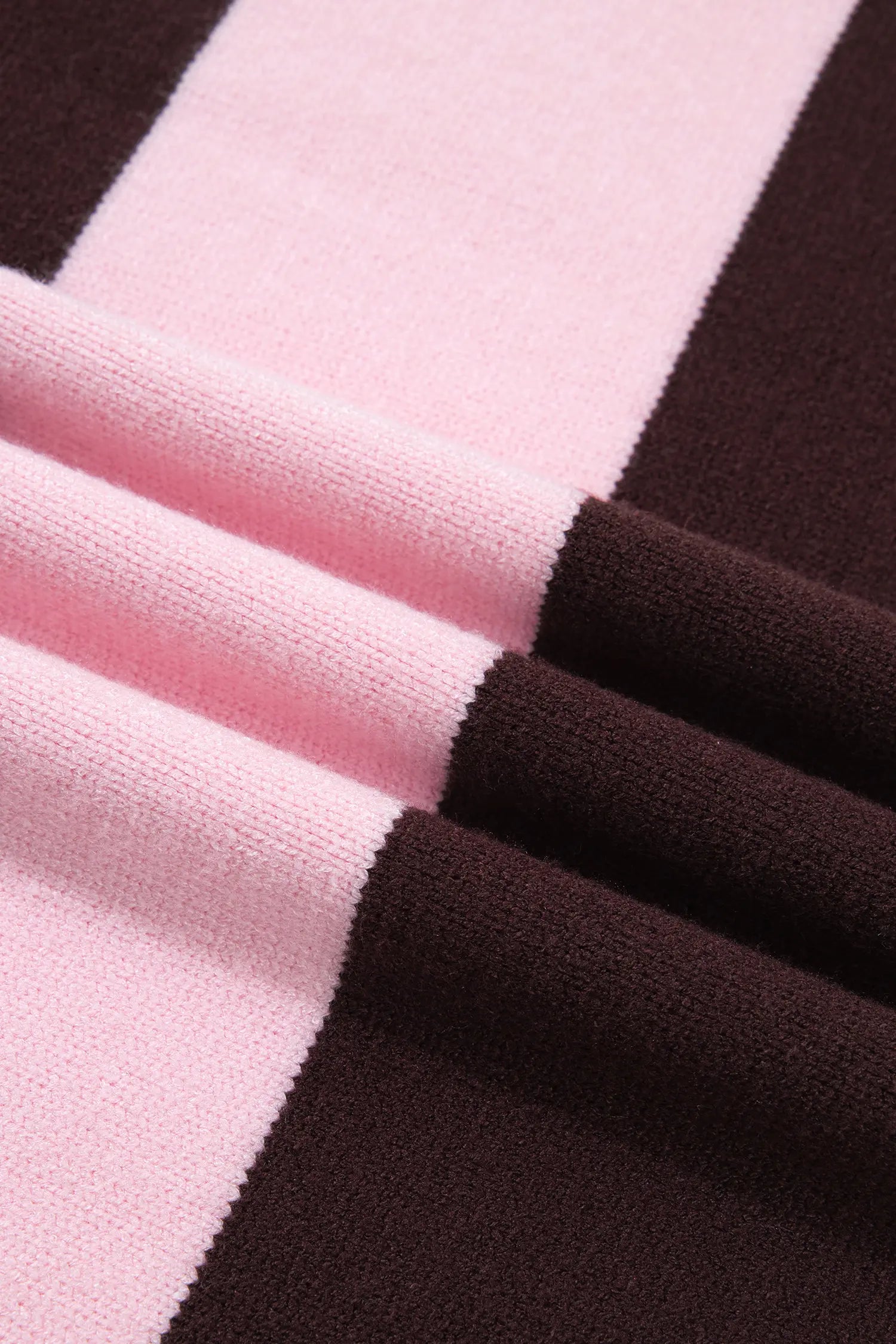 A close-up of a knit fabric with wide alternating stripes of light pink and very dark brown, shown with soft folds.