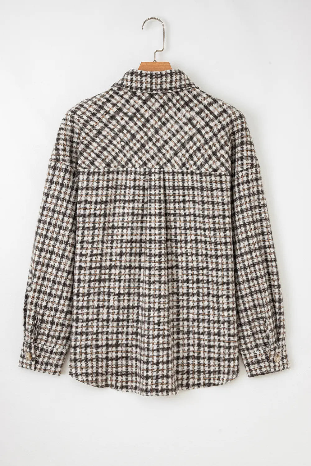 A long-sleeve plaid button-up shirt in brown, beige, and white, hanging on a wooden hanger against a plain white background.