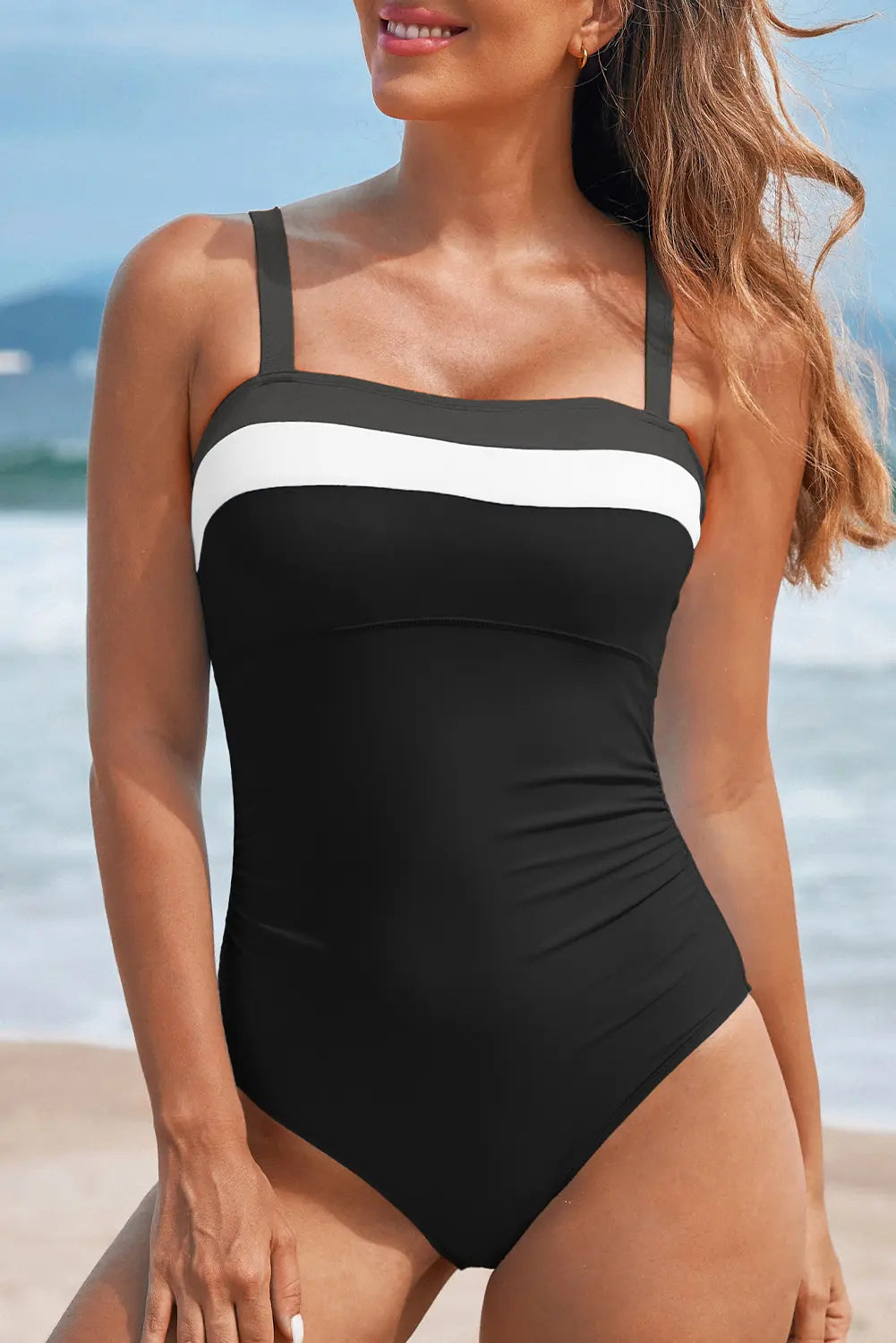 Woman wearing a black and white swimsuit with a beach background
