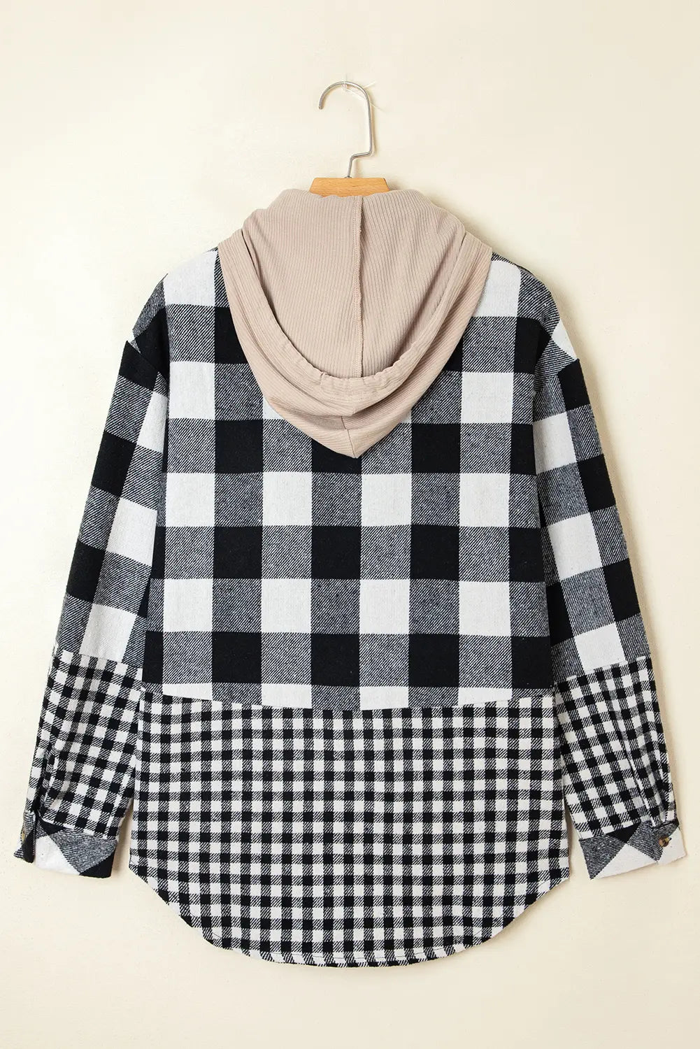 Black and white checkered shirt with beige hood on a hanger against a beige background
