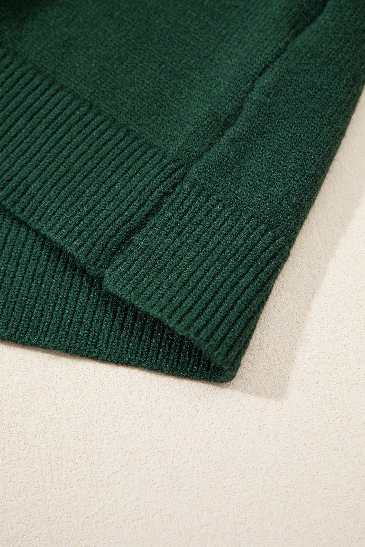 Close-up of dark forest green ribbed knit fabric with folded corner.