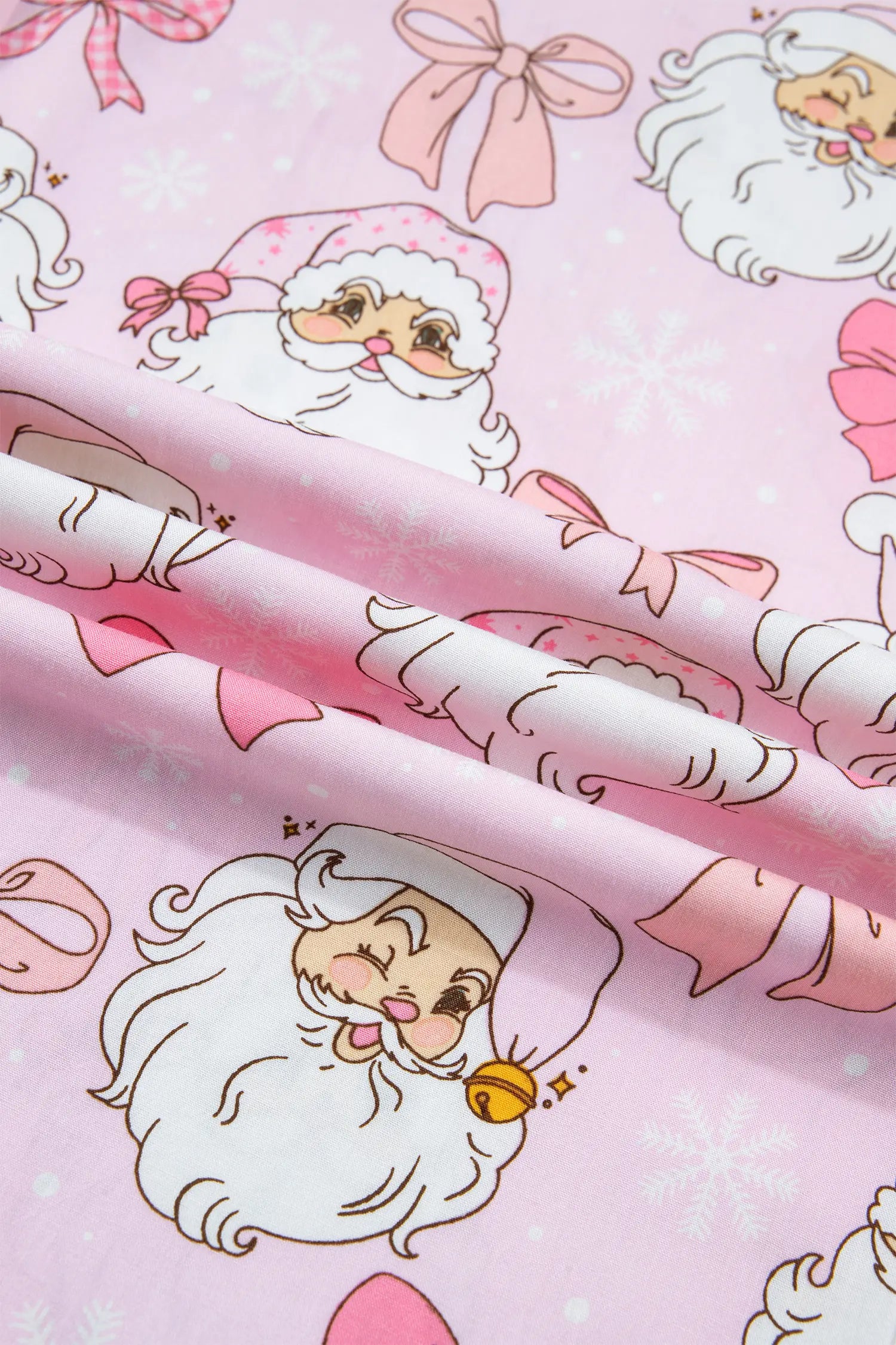 Pink wrapping paper with a cartoon Santa Claus pattern, shown with two rolled sheets of the paper.