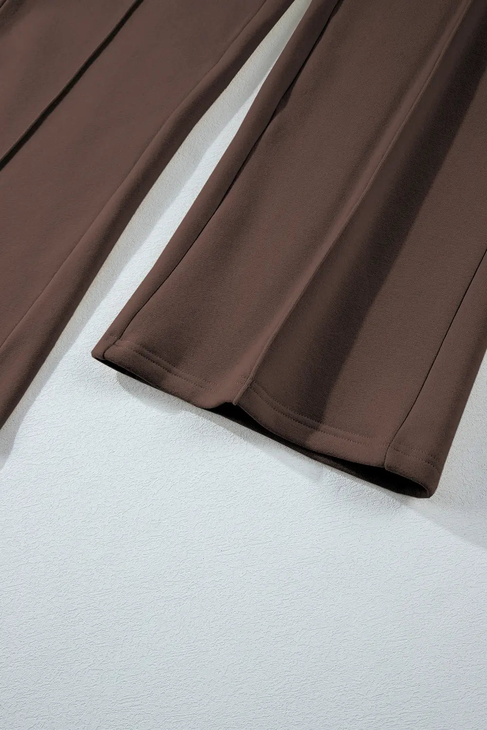 Close-up of brown wide-leg trousers showing fabric texture and hem.