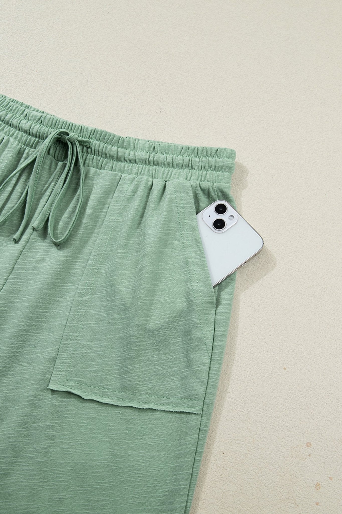 Green pants with a phone in the pocket on a beige background