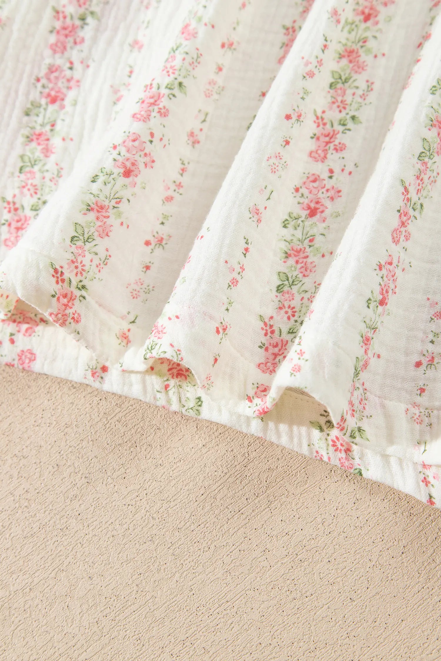 Close-up of white muslin fabric with delicate pink-green floral print.