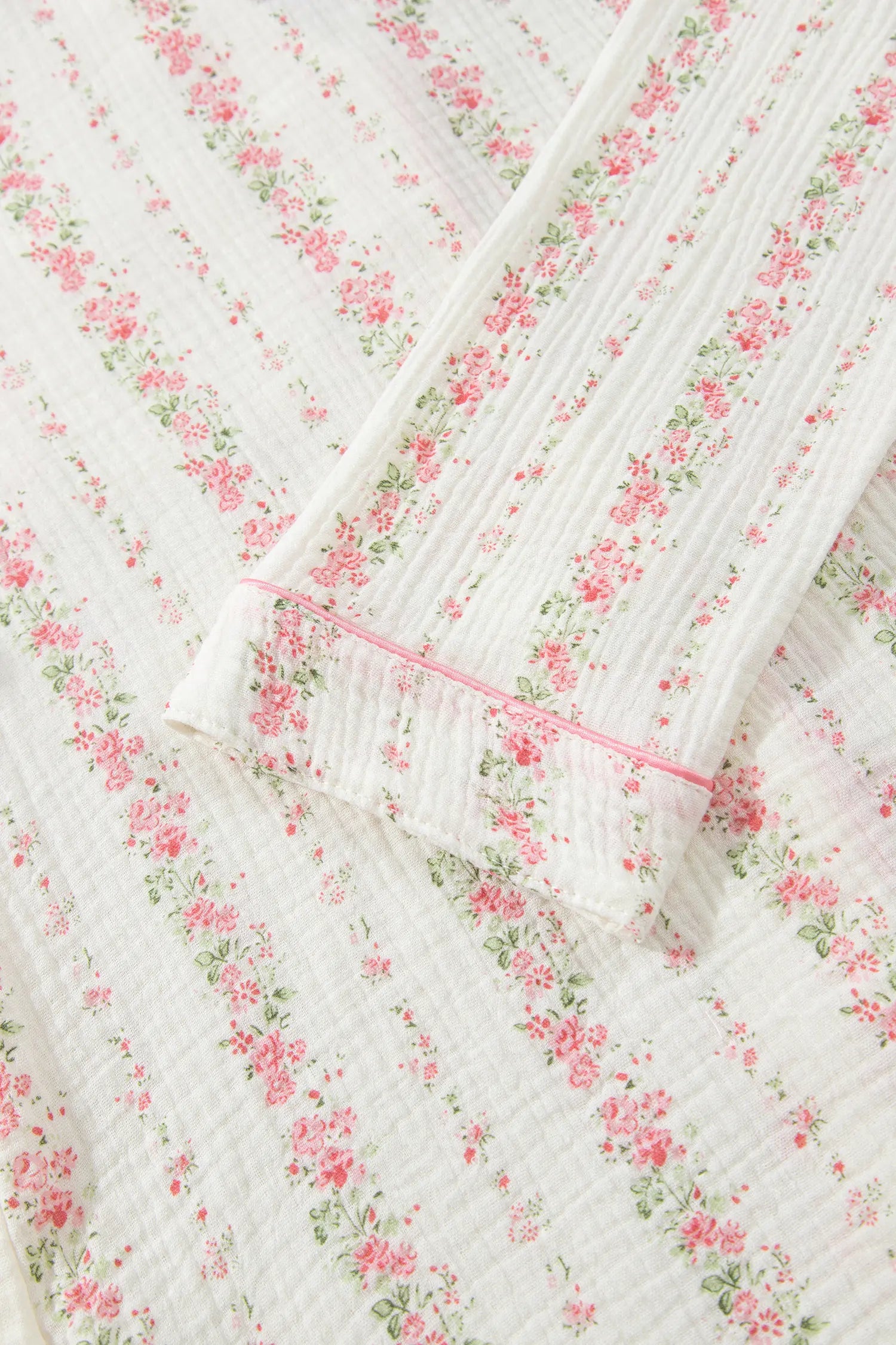 Close-up of white cotton pajama top with pink-green floral stripes and pink piping.