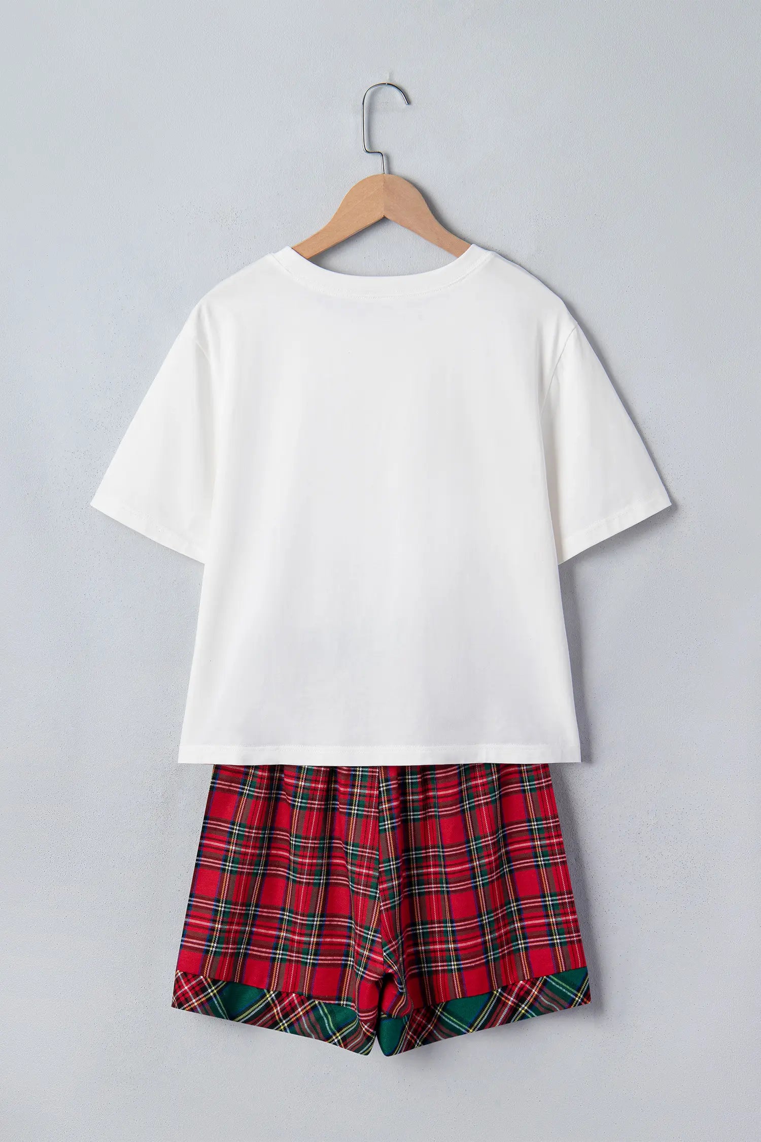 White short-sleeve tee with red, green, and black plaid shorts on hanger.