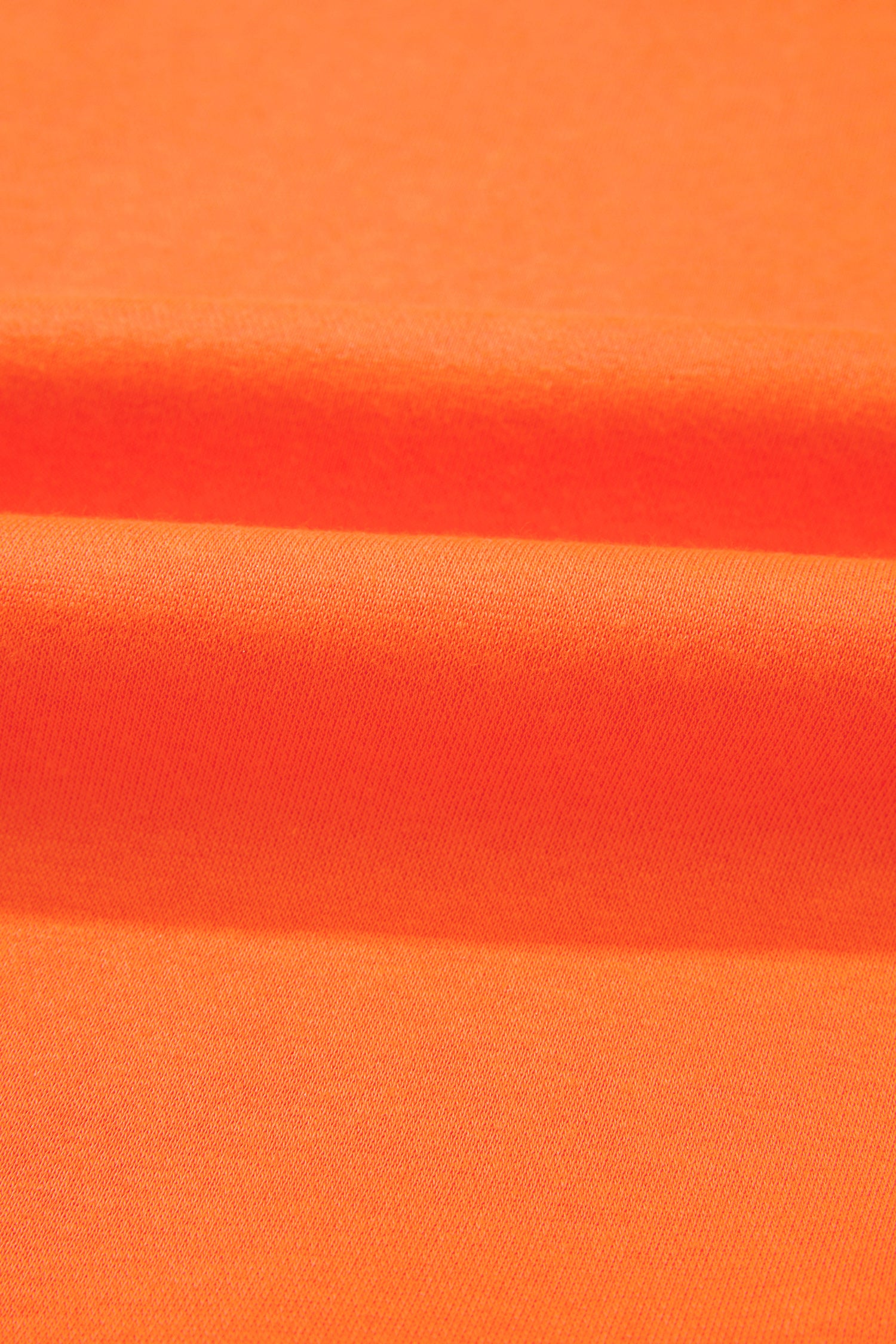 A close-up of bright orange fabric with soft horizontal folds and a smooth texture.