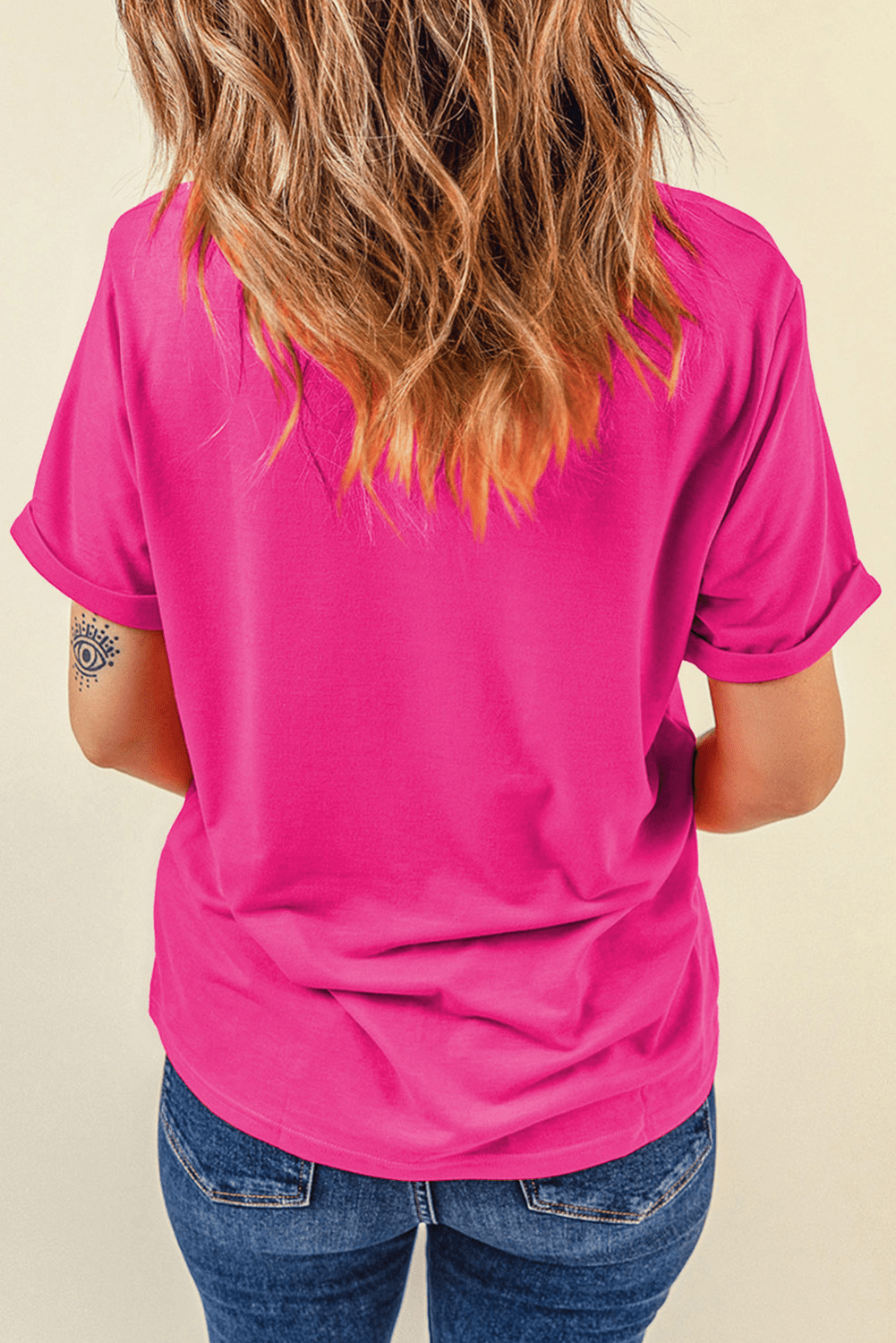 Person wearing a bright pink t-shirt and blue jeans on a beige background
