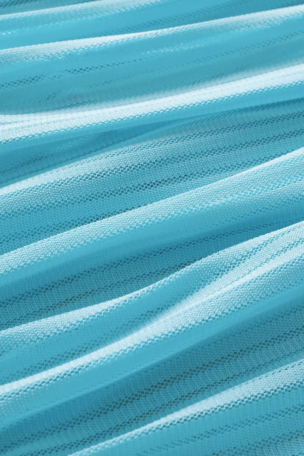 A close-up of light blue pleated mesh fabric with soft, flowing folds and a fine woven texture.