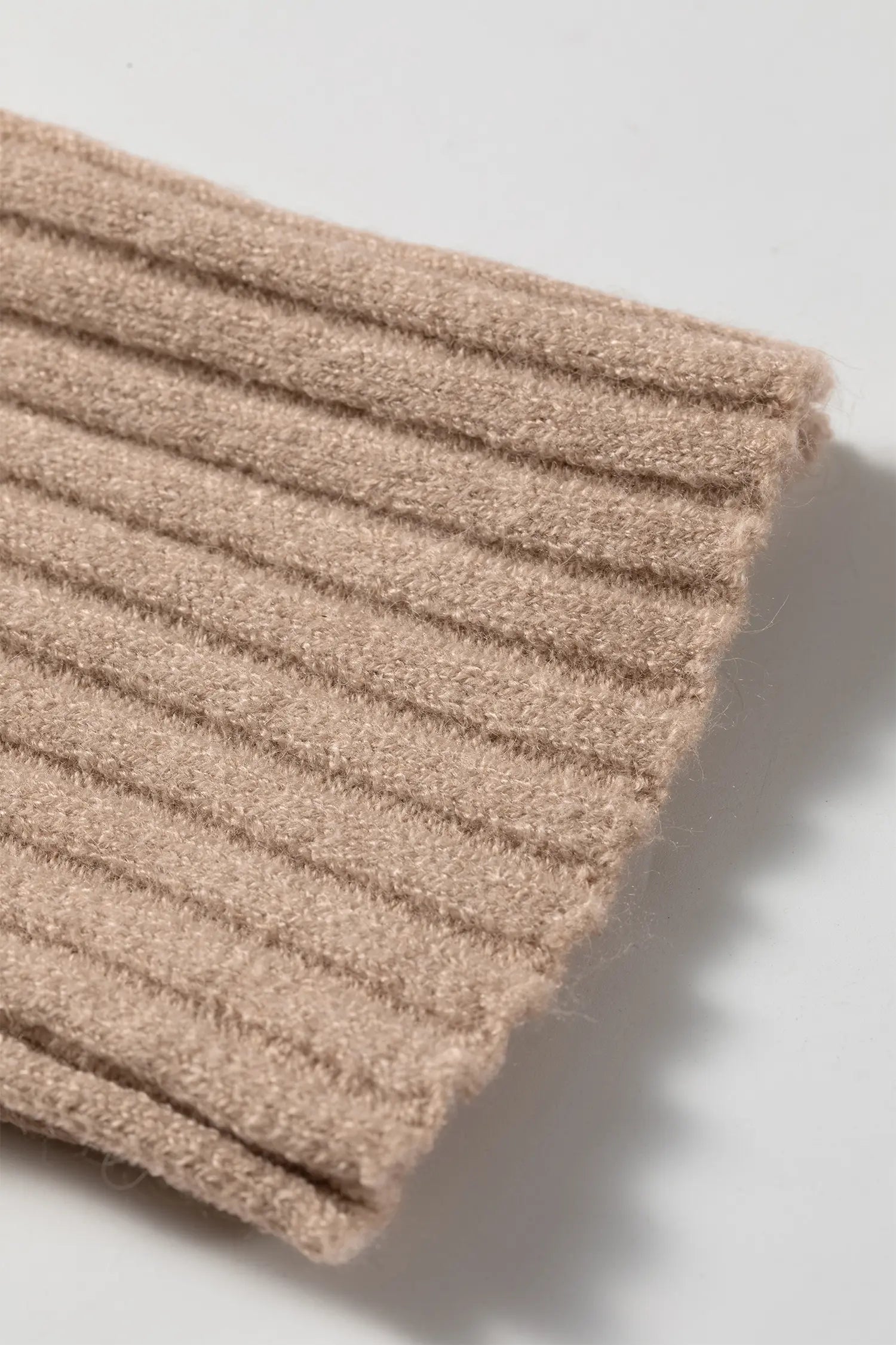 Close-up of warm taupe-beige ribbed knit cuff with textured fabric and folded edge.