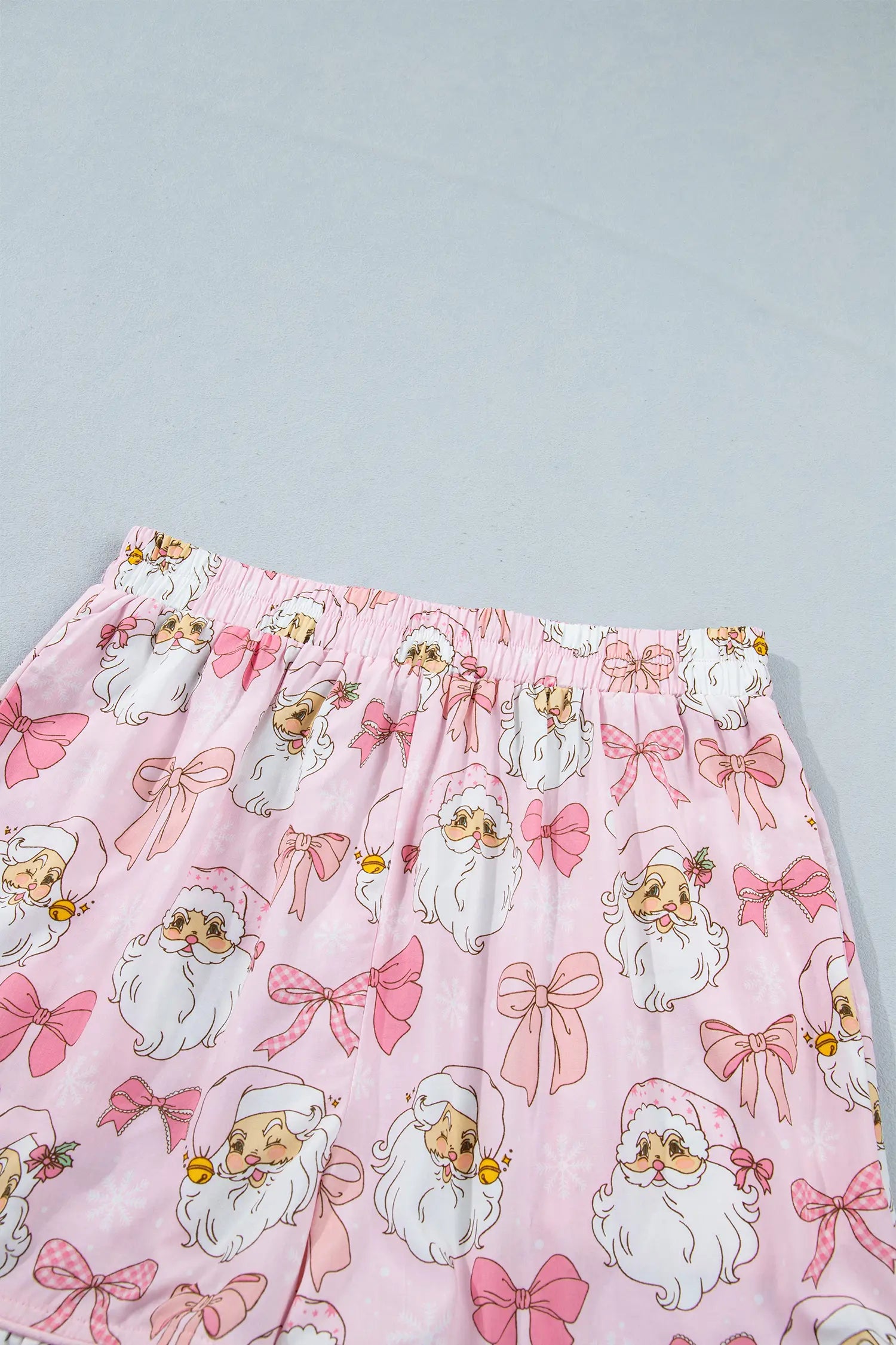 Pink pajama pants with Santa faces, pink bows, and yellow bells print.