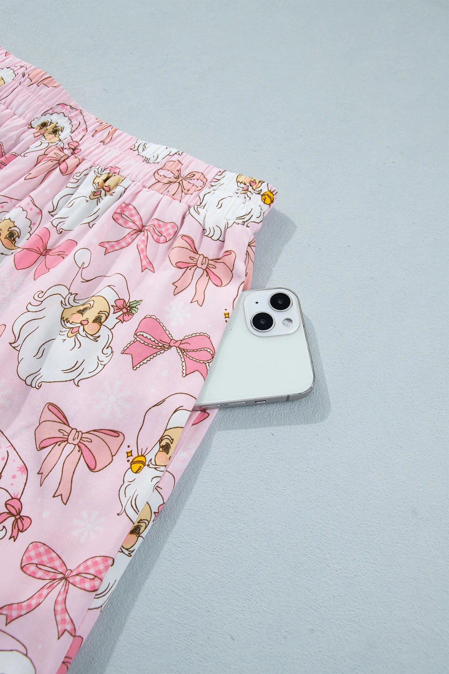 Pink shorts with cartoon angel and pink bow print beside smartphone.
