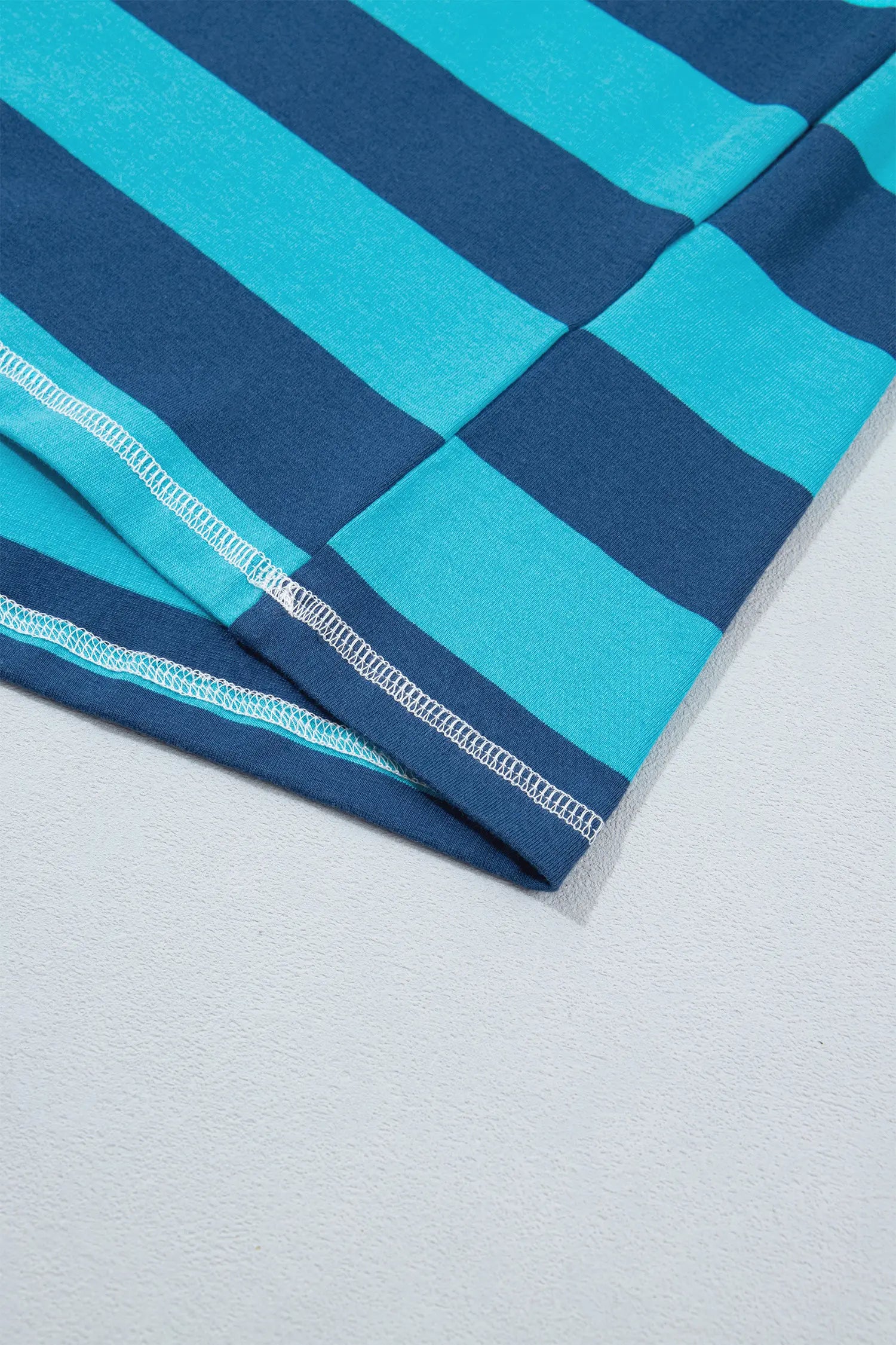 Folded navy and turquoise striped fabric on a light gray surface.