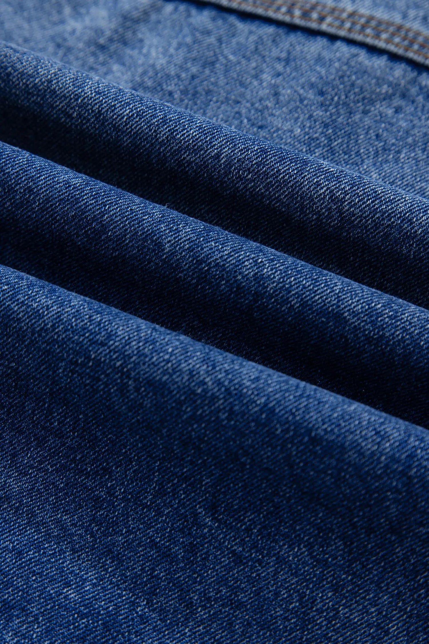 A close-up of dark blue denim fabric with a diagonal twill texture 